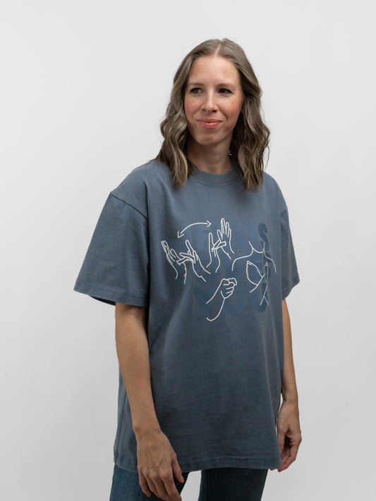 Person wearing a blue t-shirt with white graphics on a plain background