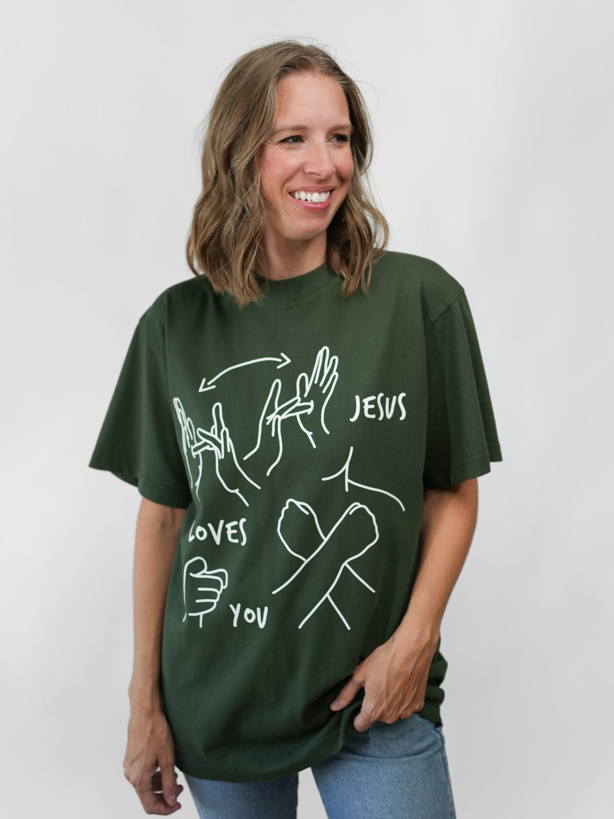 Woman wearing a green t-shirt with white graphics and text on a plain background