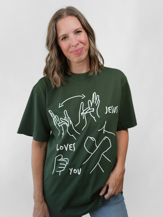 Woman wearing a green t-shirt with white graphics and text on a plain background