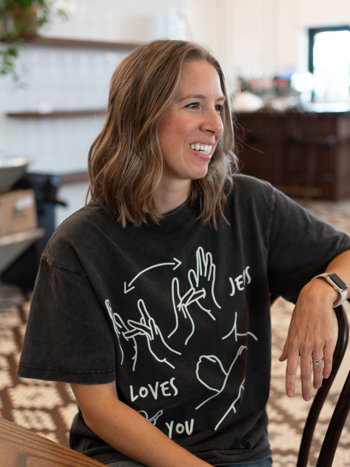 Woman wearing a black t-shirt with white graphics in a cafe setting