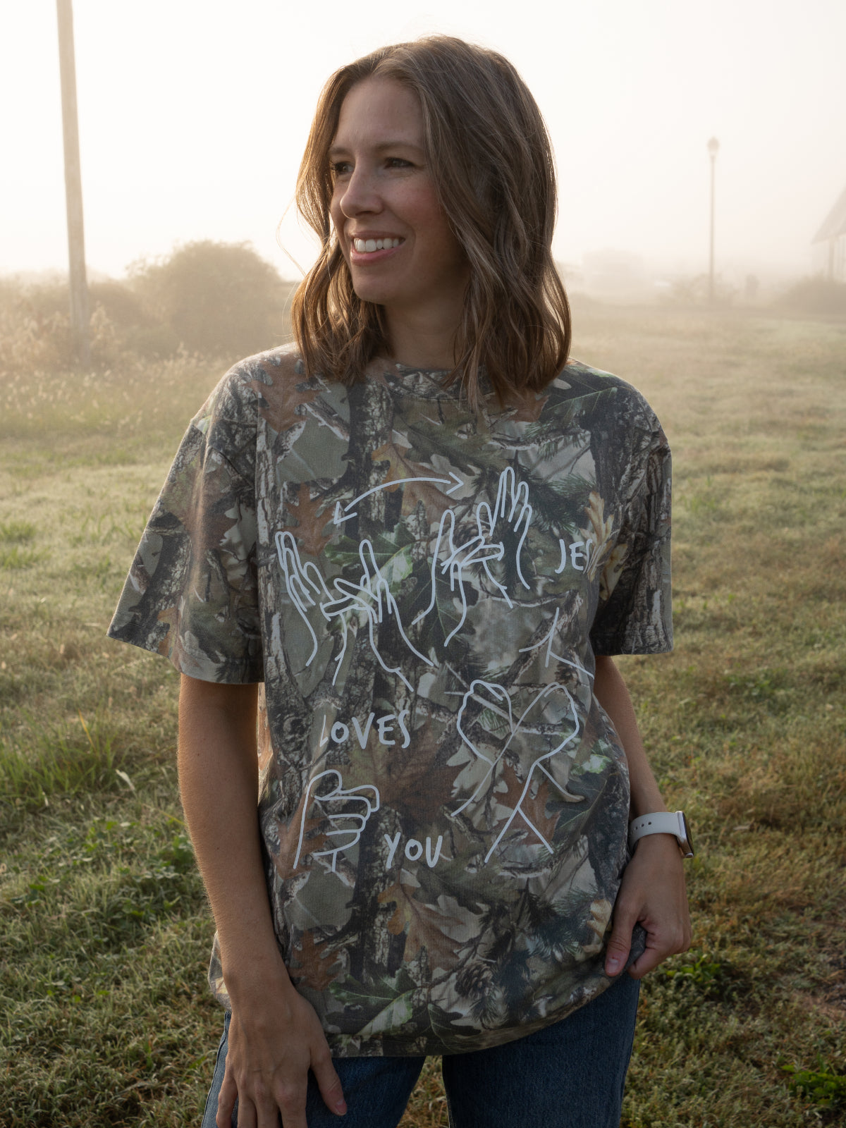 Woman wearing a camouflage t-shirt with white graphics in an outdoor setting