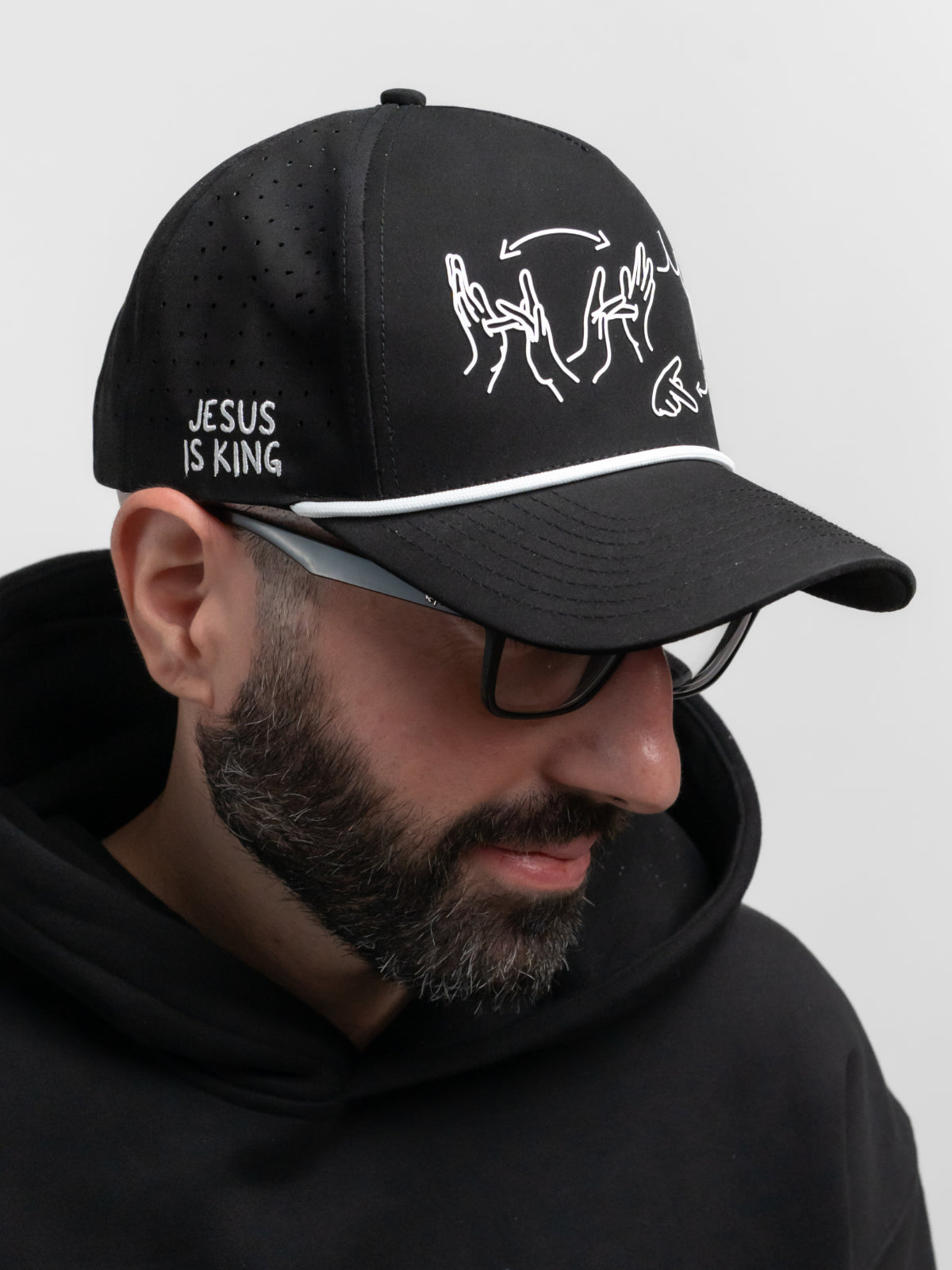 Person wearing a black cap with white text and graphics, set against a plain background