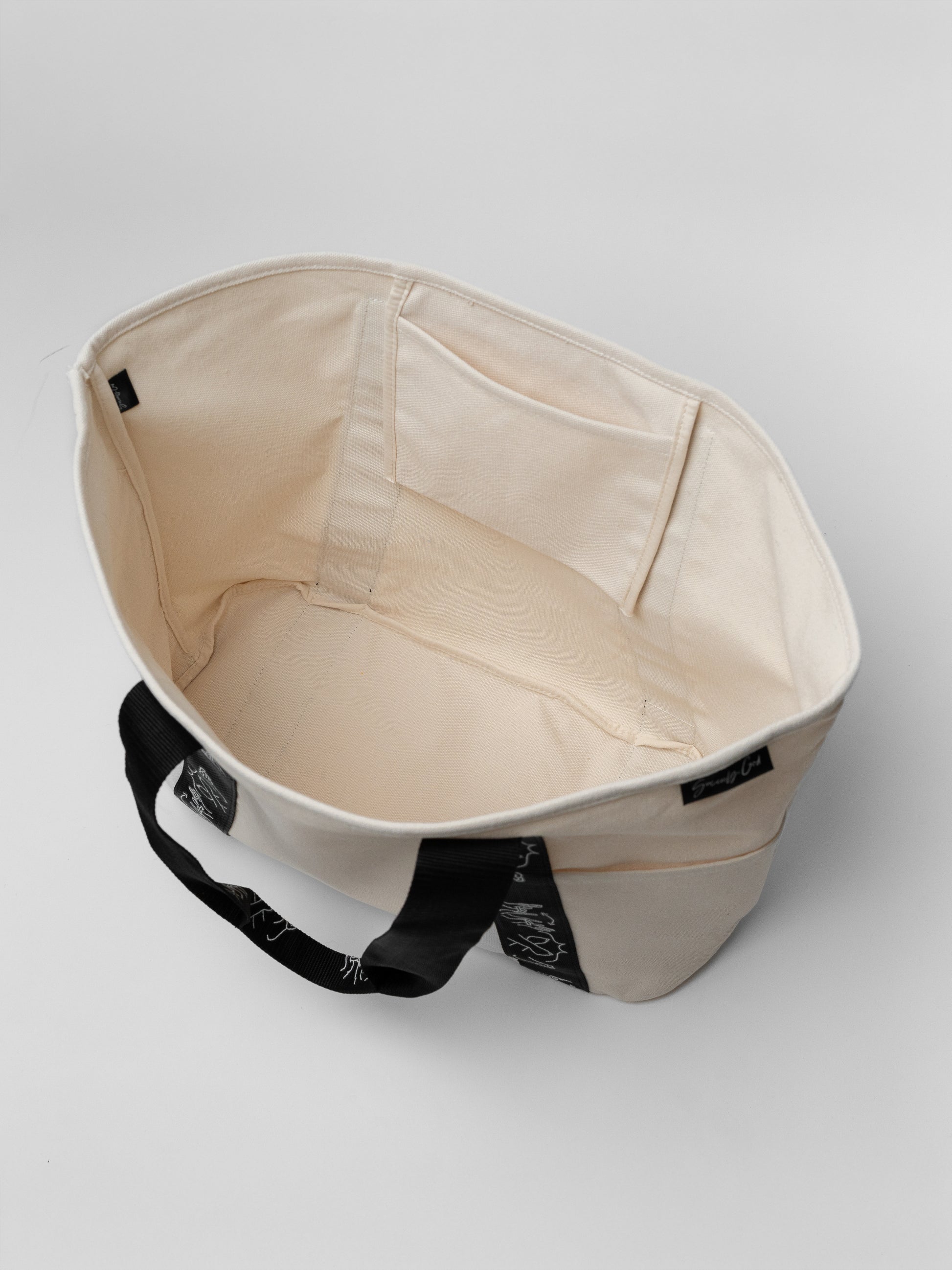 Beige bag with black handle on a light gray background