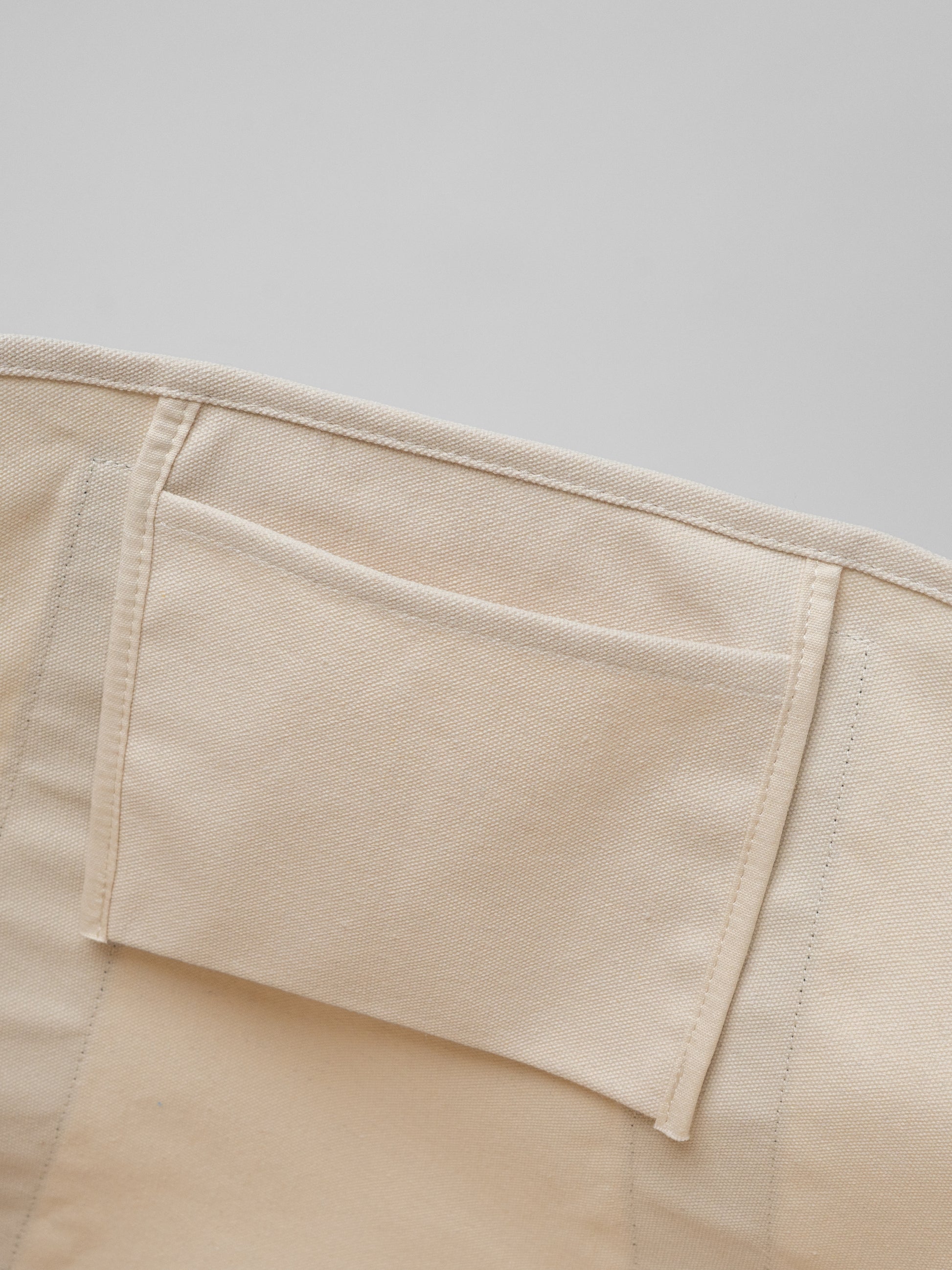 Close-up of beige pants with a pocket on a light gray background