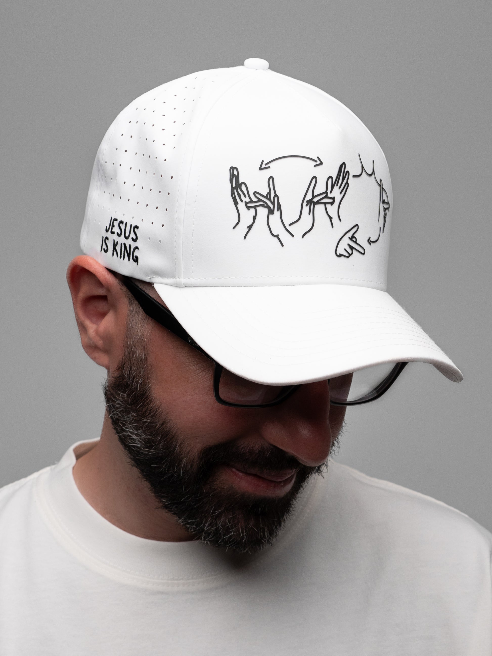 Person wearing a white cap with black text and graphics on a gray background