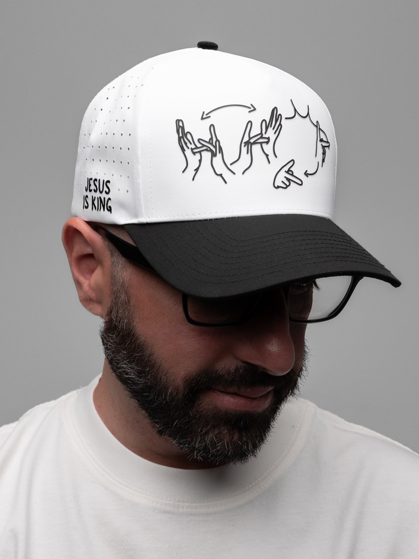 Man wearing a white cap with black text and graphics on a gray background